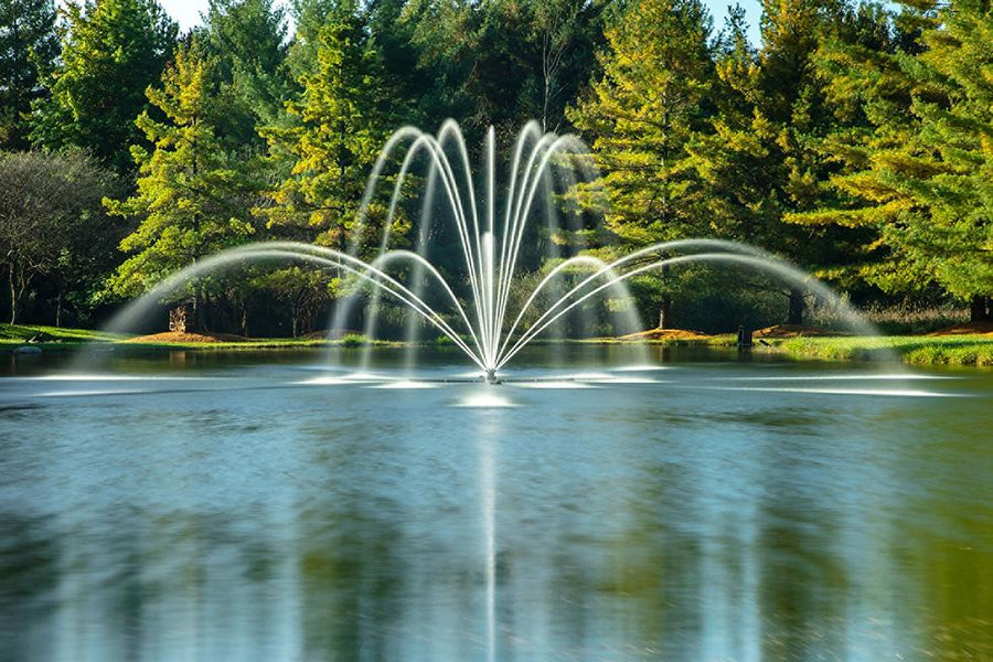 Decorative floating pond fountain with a water spray display in a landscaped pond